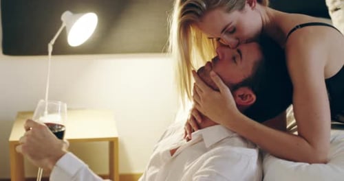 Affectionate Couple Kissing in Bedroom with Wine