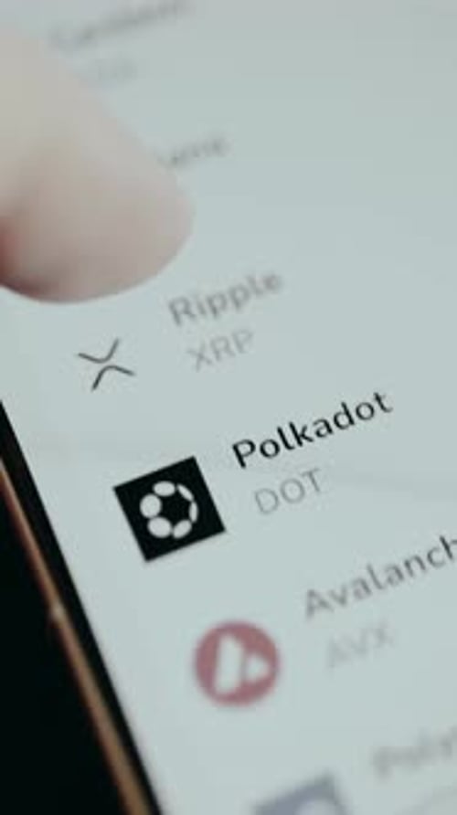 Person Scrolls a List of Cryptocurrency Assets and Their Perspective Ticker Symbols