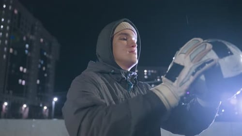 Side View of Footballer Tossing Soccer Ball During Night Training Session