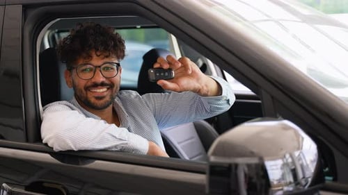 Happy Customer Showing New Car Key While Sitting in Vehicle