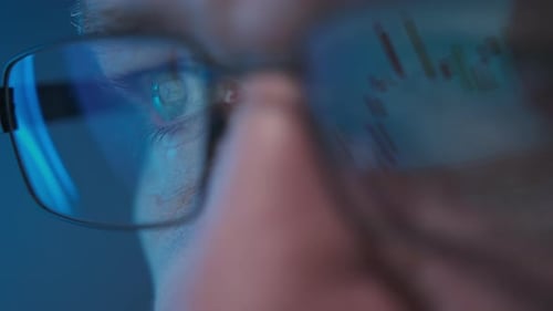 Stock Market Trader Working Investment Charts Graphs Ticker Diagrams Projected on Reflecting in