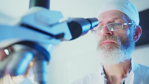Focused Scientist Using Microscope in Modern Lab