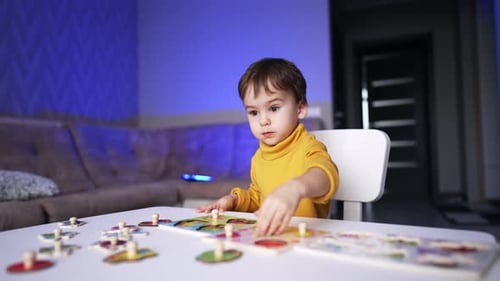 Beautiful dark-haired baby boy in yellow sweater sitting at desk.