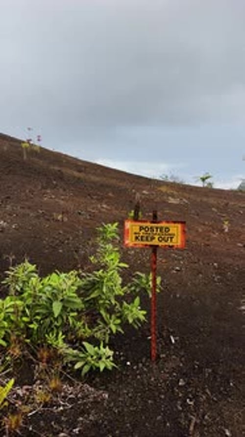 Rusty Warning Sign Against Barren Hawaii Volcanic Landscape