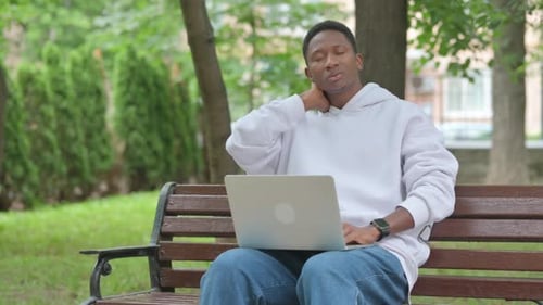 Young Man Using Laptop on Park Bench