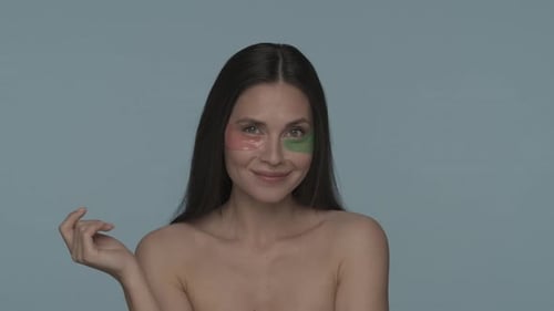 Portrait of a Seminude Woman with Various Hyaluronic Patches Under Her Eyes on a Blue Background