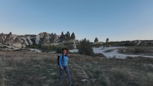 Reisendes Mädchen mit Rucksack und Hut wandert zwischen den Felsen von Kappadokien