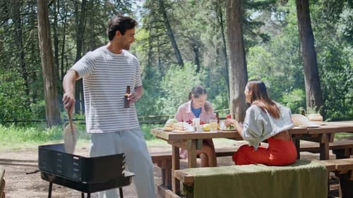 Family Enjoying Summer Barbecue Picnic in Sunny Park Man Grilling Food Outdoors