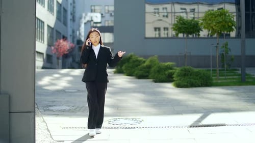 Business woman or university college student in a suit walks down a city street, talks and uses
