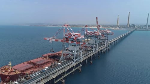 Aerial footage of a Large Bulk carrier offloading coal for a large scale power plant