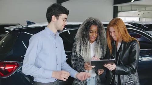 Car Salesman Talking to Happy Customers in Showroom