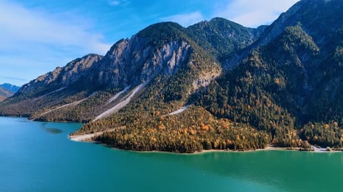 Beautiful Alps covered with pine trees with a turquoise waterscape at the foot.