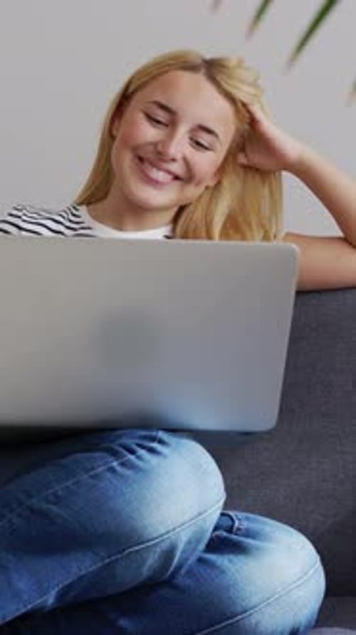 Blonde Woman Works on Laptop While Sitting on Couch