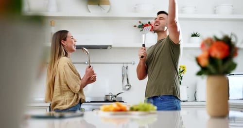 Young Couple Dancing and Singing in Kitchen