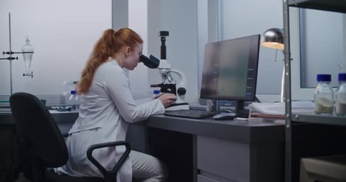 Woman Analyzing Sample with Microscope in Bright Lab