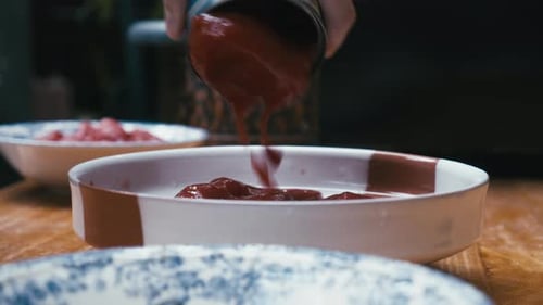 Chef pulls down tomatoes onto a plate. Close up.