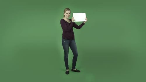 casual caucasian blond girl isolated on green smiling with blank sign