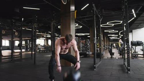 Muscular sportsman training in gym.