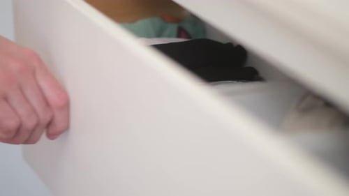 A woman's hand opens a drawer, close-up. Cabinet drawer