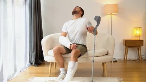 Man Sitting With Leg Cast and Arm Cast