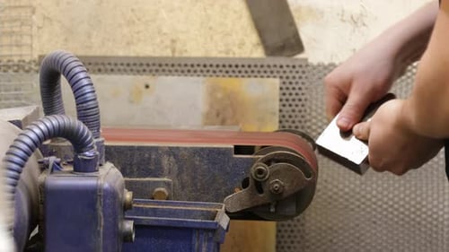 Factory Worker Polishing The Edges And Surface Of Metal Block With Linishing - close up shot