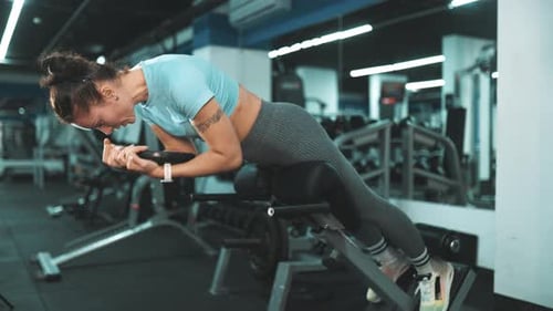 Athletic Woman Performing Hyperextension Exercise in Gym