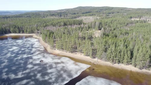 Aerial view of a secluded lake in the woods with houses in background.
