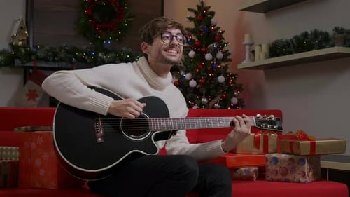Young Man Plays Guitar at Christmas Time