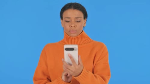 Casual African Woman using Phone on Blue Background, Portrait