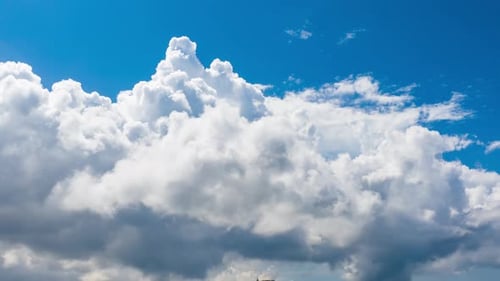 Timelapse of white puffy cumulus clouds forming on summer blue sky.