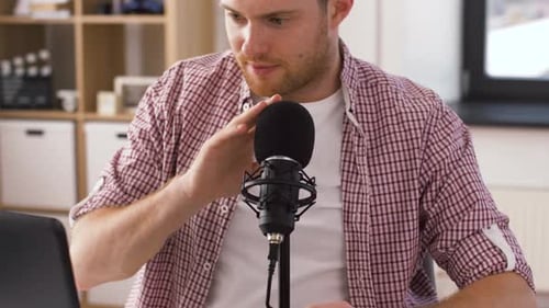 Young Man Adjusting Microphone For Podcast At Desk