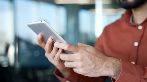 Close up of male hands holding digital tablet at desk at workplace in modern business office.