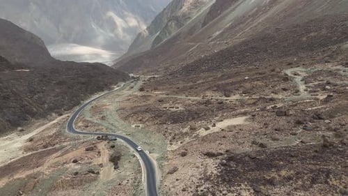 Luftaufnahme von oben nach unten eines weißen Autos, das auf kurvigen Straßen der Berge fährt