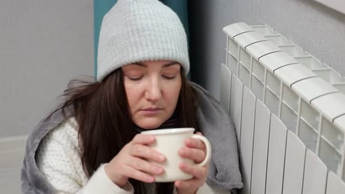 Woman Drinks Hot Beverage and Tries to Warm Up From Battery