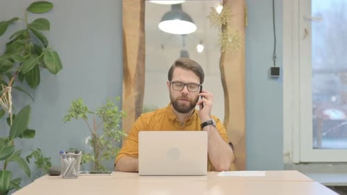 Young Businessman Talking on Phone in Office