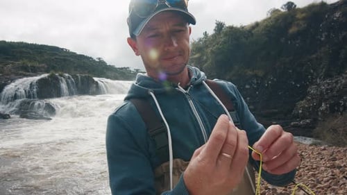 Fisherman Prepares Fishing Line By Rushing River