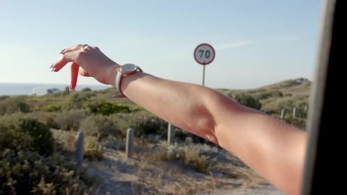 O braço de uma pessoa é estendido para fora da janela de um carro, aproveitando a brisa em uma viagem com espaço de cópia