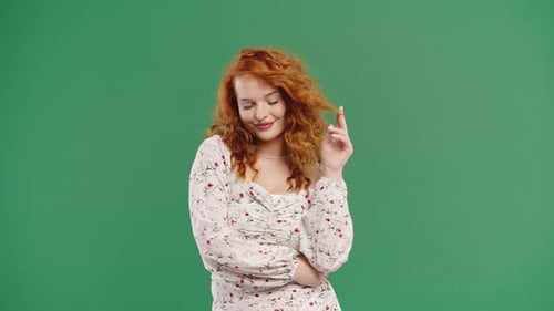 Playful Redhaired Curly Woman Smiling Flirting To Camera On Green Studio