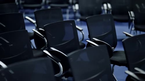 Empty Rows of Modern Black Chairs in a Dimly Lit Auditorium Highlighting Repeated Patterns Sleek