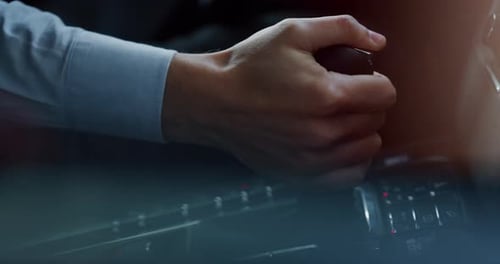 Close-up de um empresário movendo manualmente a transmissão de um carro moderno de luxo anônimo de prestígio.
S