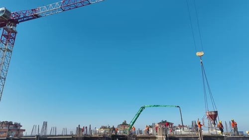Luftbild einer großen Baustelle, auf der Arbeiter Beton gießen und Materialien anheben