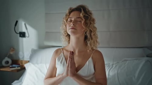 Woman Meditating on Bed in a Bedroom