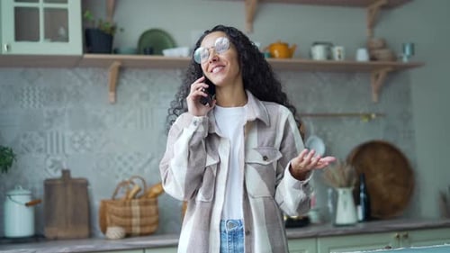 Happy Woman Chatting on Phone in Cozy Kitchen