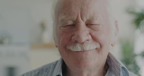 Closeup Portrait of Cheerful Elderly Man Smiling Looking at Camera Indoors in Apartment