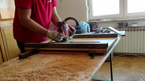 Woodworker working withe milling router machine in small home workshop. Flattening live edge wood fo