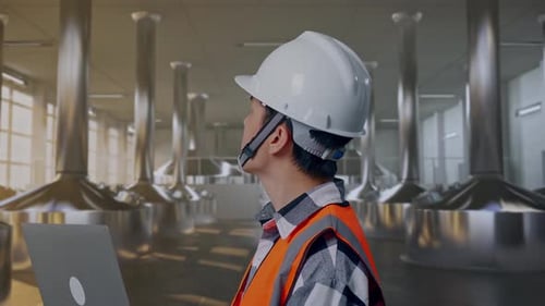 Close Up Side View Of Asian Male Engineer Working On A Laptop at Beer Plant