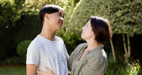 Teen with Braces Hugs Smiling Woman in Garden