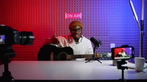Man Playing Guitar in Colorful Podcast Studio