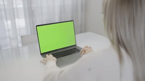 Una mujer trabajando en su portátil con una pantalla verde