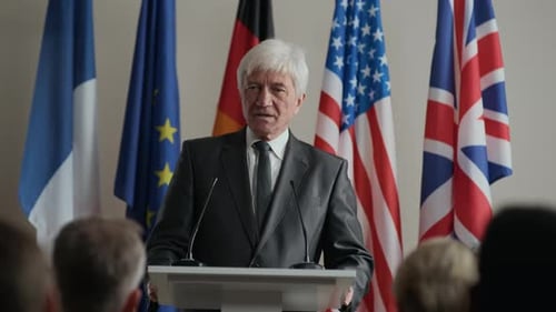Man Speaking at Podium with Flags in Background